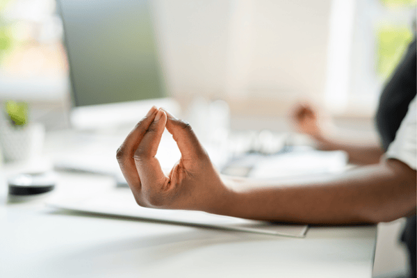 A professional meditating at their desk, highlighting mental and emotional wellness at work.